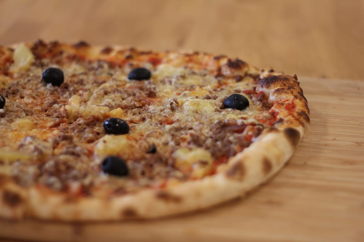 Pizza Bolognaise garnie de Sauce tomate, Oignons confits, Pomme de terre, Steak haché, Emmental français et Mozzarella