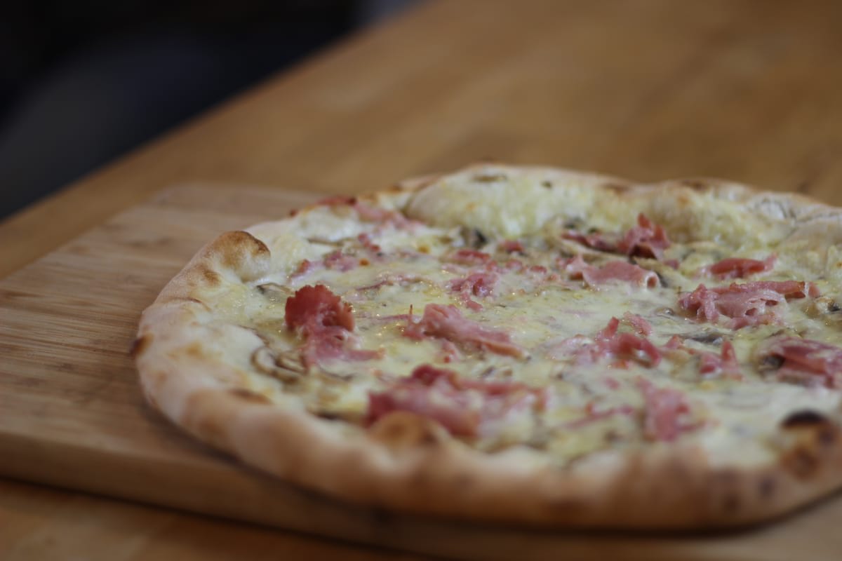 Pizza Campagnarde garnie de Crème fraîche, Champignons, Jambon, Lardons et Emmental français