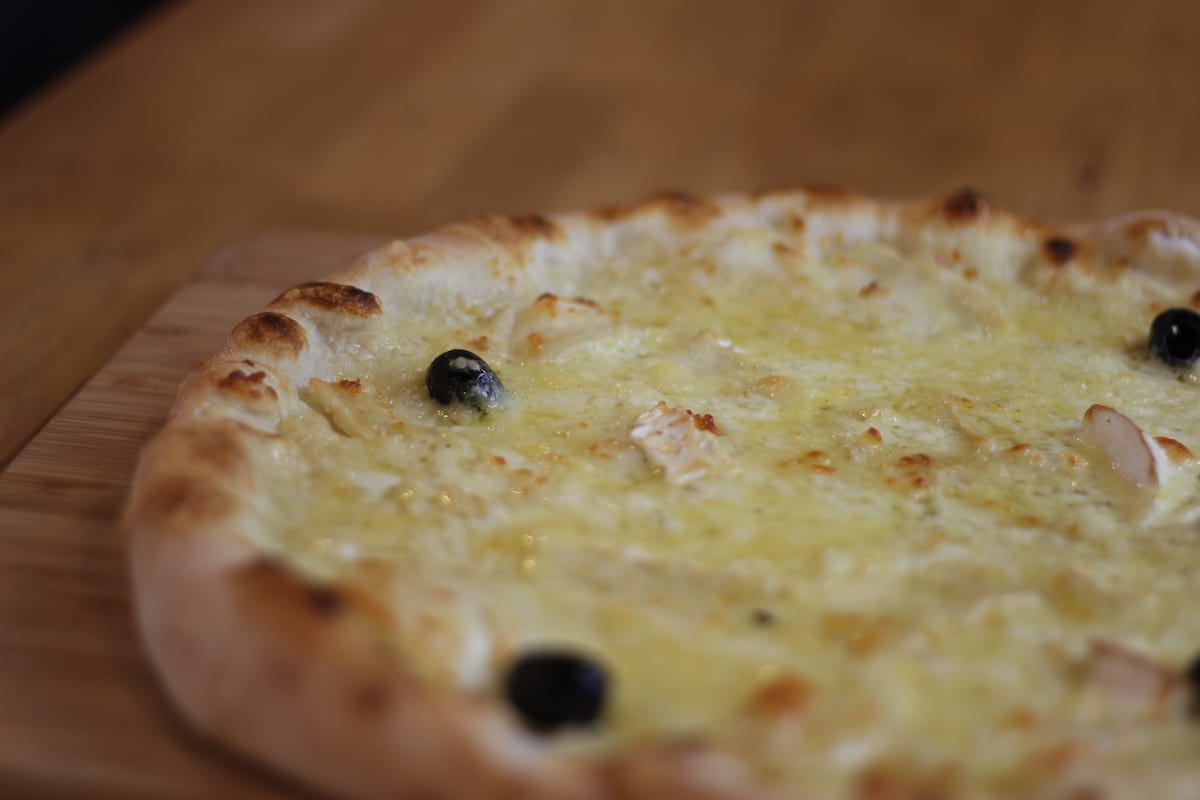 Pizza Chèvre-miel garnie de Crème fraîche, Emmental français, Fromage de chèvre et Miel