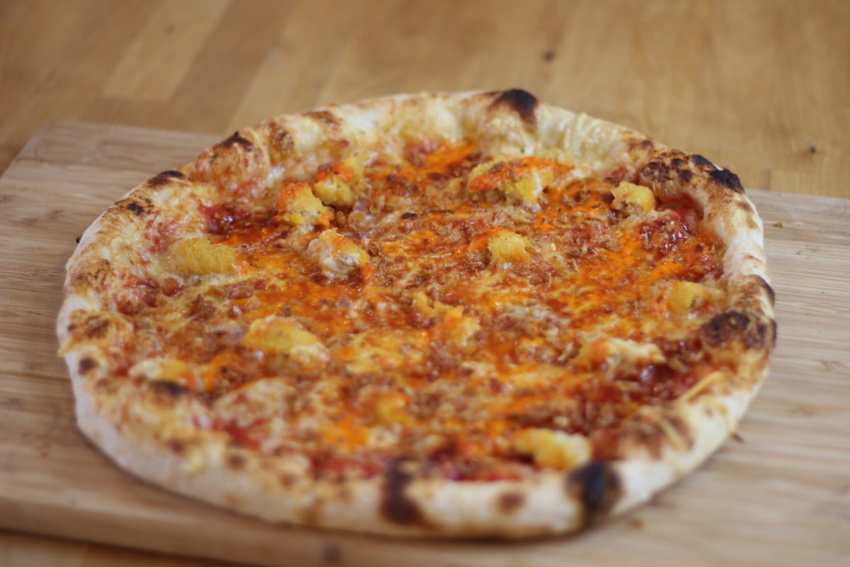 Pizza Cryspy garnie de Sauce tomate, Oignons frits, Poivrons, Poulet pané, Emmental français et Sauce barbecue