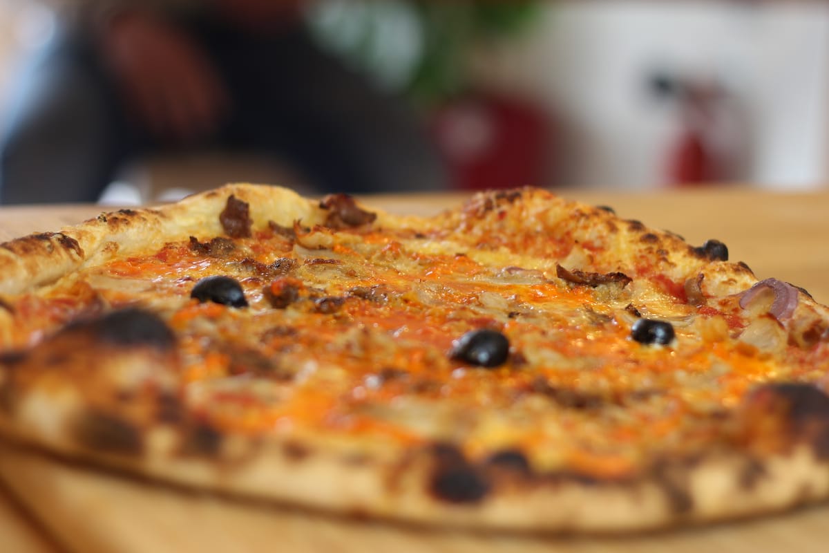 Pizza Kebab garnie de Sauce tomate, Oignons confits, Poivrons, Kebab, Emmental français et Olives noires