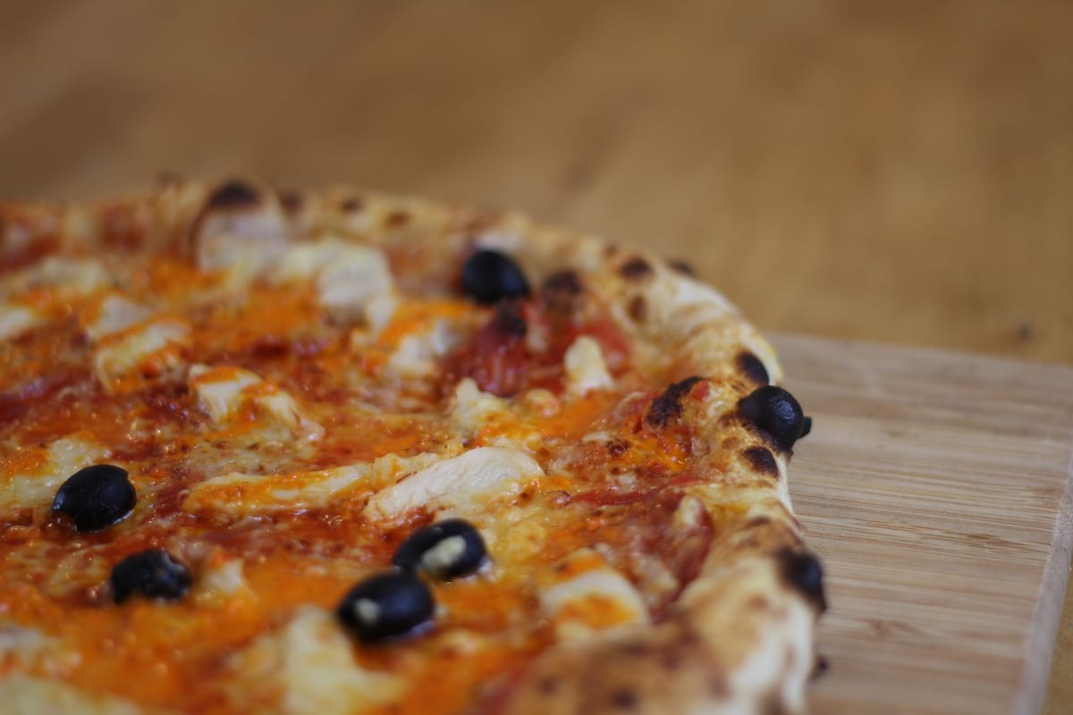 Pizza Kentucky garnie de Sauce tomate, Oignons confits, Poivrons, Chorizo, Poulet et Emmental français