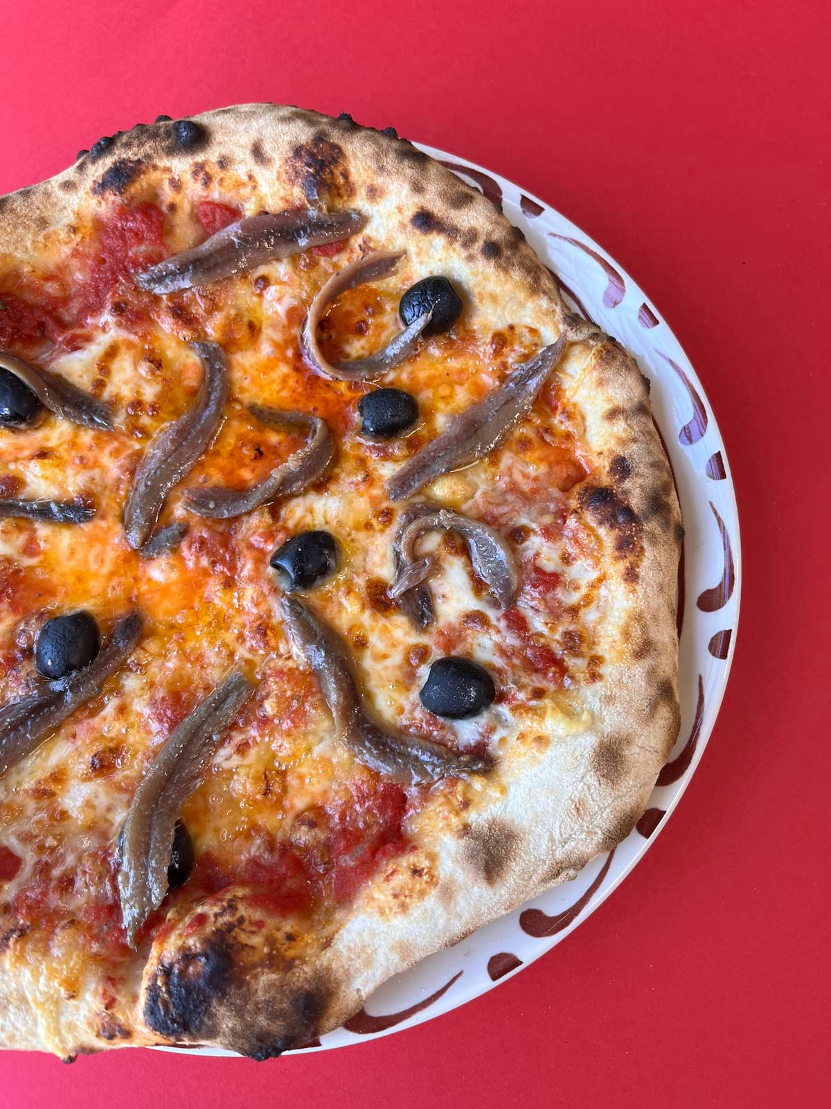 Pizza Napolitaine garnie de Sauce tomate, Anchois, Emmental français et Olives noires