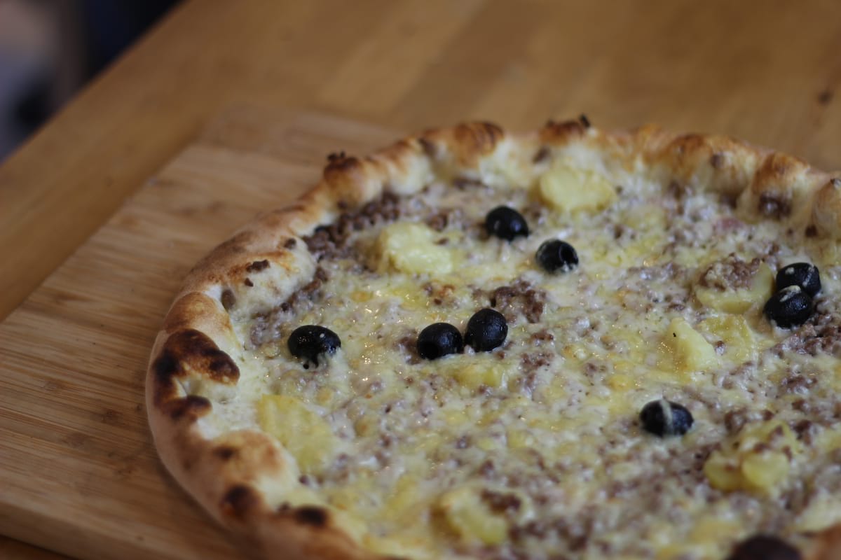 Pizza Parmentière garnie de Crème fraîche, Oignons confits, Pomme de terre, Steak haché et Emmental français