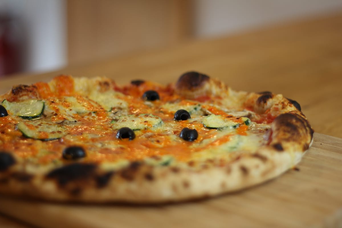Pizza Quatre saisons garnie de Sauce tomate, Aubergines, Champignons, Courgettes, Poivrons, Emmental français et Olives noires