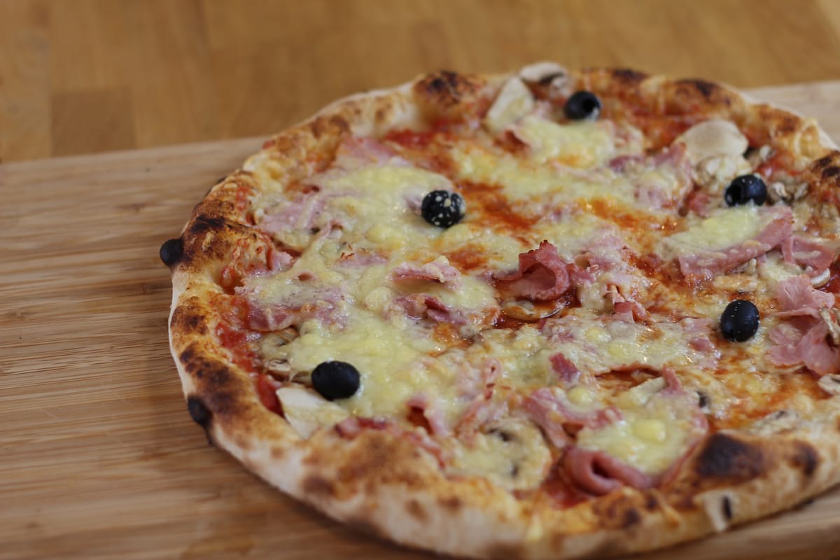 Pizza Royale garnie de Sauce tomate, Champignons, Jambon, Emmental français et Olives noires